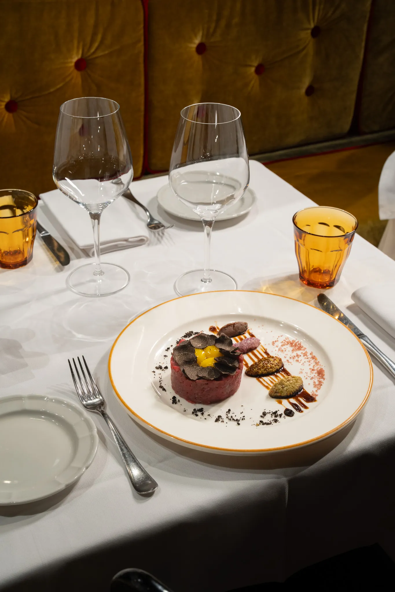 Tartare with black truffle, amber glasses, gold velvet banquette
