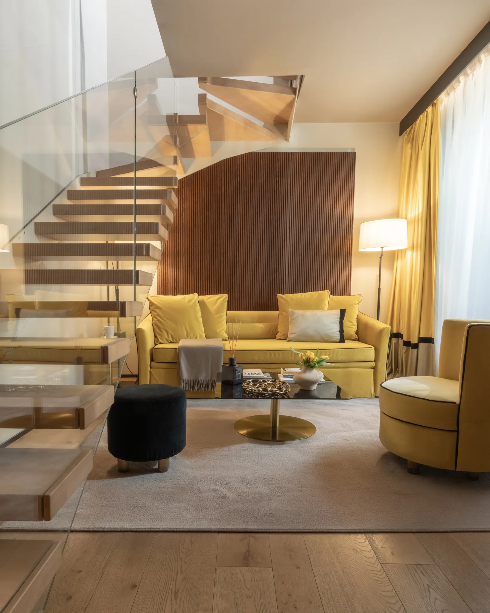 Suite Duplex — glass staircase from below, light filtering through